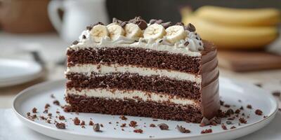 Delicious chocolate banana cake with layers, cream, and chocolate chips presented on a white plate photo