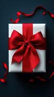 Gift package with red ribbon placed on dark surface for special occasions and celebrations photo