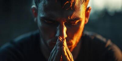 Man in deep concentration with hands clasped near face under warm lighting during evening hours photo