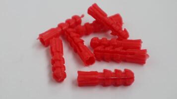 a pile of red plastic drywall anchor on a white surface photo