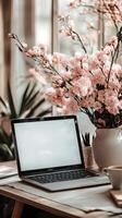 Stylish workspace with laptop and blooming flowers near natural light during the afternoon photo