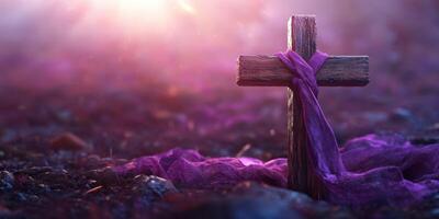 Wooden cross wrapped in purple cloth with soft light illuminating the background during a serene moment at twilight photo