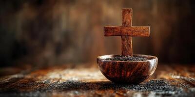 Wooden cross placed in a rustic bowl with soil on a textured wooden surface photo