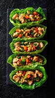 Delicious chicken lettuce wraps with colorful vegetables served on a black slate plate photo