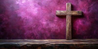 Wooden cross displayed against a textured purple background with rustic wooden table in soft lighting photo