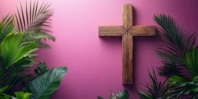 Wooden cross adorned with lush green plants against a vibrant pink wall in a tranquil setting photo