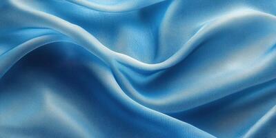 Soft blue fabric drapes elegantly in gentle waves, showcasing its smooth texture and vibrant color under ambient light photo