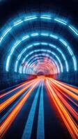Bright neon lights illuminate a modern tunnel at night with streaks of light from moving vehicles photo