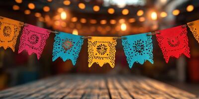 Colorful papel picado banners hanging over a wooden table in a lively festive setting with warm lights photo