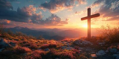 Cross silhouette against a colorful sunset over mountain landscape with blooming flowers photo