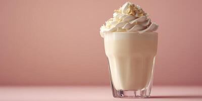 Creamy milkshake topped with whipped cream and nuts against a soft pink background photo