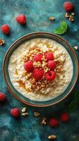 Creamy oatmeal topped with fresh raspberries and crunchy granola placed on a vibrant teal background photo