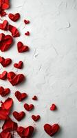Red paper hearts scattered artistically on a textured white surface for a romantic theme photo