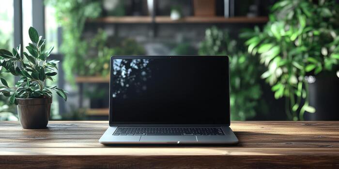 Desktop setup with a closed laptop and potted plant in a well-lit indoor space surrounded by greenery photo