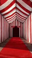 Striped tent entrance with red carpet leading into dark space at a circus or fair setting photo