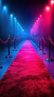 Elegant red carpet pathway flanked by velvet ropes and colorful lights in a venue prepared for a glamorous event photo