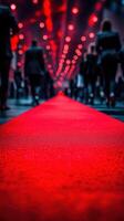 Busy crowd walking on a bright red carpet illuminated by glowing lights in a vibrant indoor setting during a nighttime event photo