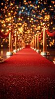 Elegant red carpet pathway adorned with ropes and golden posts, leading to a sparkling event under bright festive lights photo