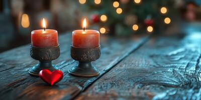 Two glowing candles on a rustic wooden table with a heart decoration and blurred Christmas lights in the background photo