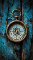 Vintage compass hangs against weathered blue wood, showcasing timeless navigation charm and historical craftsmanship photo