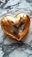 Golden heart-shaped object resting on a marble surface, reflecting light and creating a beautiful contrast photo