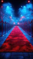 Red carpet lined with ropes under dramatic blue lights in a glamorous setting during a nighttime event photo