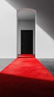 Red carpet leading to a black door in a minimalist architectural space with natural light photo