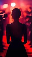 Elegant figure in silhouette on the red carpet at a glamorous evening event surrounded by flashing lights photo