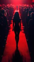 Model walks confidently down a red carpet amidst a captivated audience during a fashion event in an illuminated venue photo
