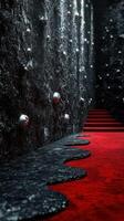 Mysterious corridor with red carpet leading up a staircase along a textured black wall with eerie decorations photo