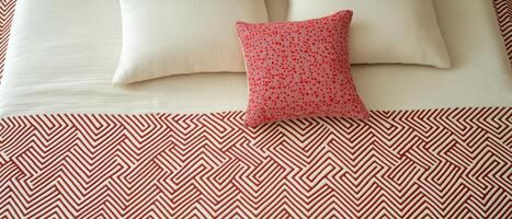 Bed Arrangement With Red Geometric Blanket photo