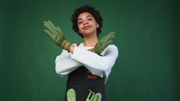 Running of own business. African woman florist gardener with pruner wearing apron isolated on green background. Happy small business owner working at flower plants shop smiling. Small business video