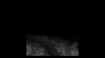 Dense dark smoke spreading along the lower edge on a black background with foggy texture. Atmospheric effect concept video