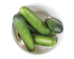 Several freshly picked cucumbers lying in white cardboard packaging, top view of fresh garden vegetables ready for culinary use isolated on white background, photo