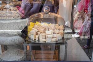Colorful pieces of fudge and other sweets are displayed under a glass dome on a platter in a shop window, enticing customers with their delicious appearance photo