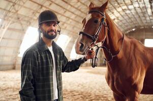 Standing, and, holding animal. Young man with a horse is in the hangar photo