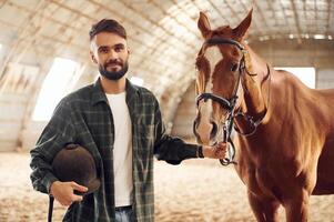 Positive emotions.. Front ,view. Young man with a horse is in the hangar photo