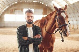 Young man with a horse is in the ,hangar photo
