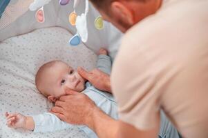 Newborn, baby, is in the cradle. Father is indoors. Conception of single dad photo