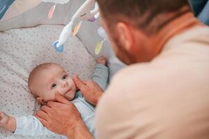 Newborn, baby is in the cradle.. Father is indoors. Conception of single dad photo