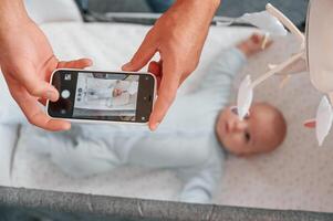 Taking ,picture by smartphone. Father with his newborn baby is indoors. Conception of single dad photo
