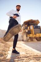 Having, fun, making a kick by leg. Man in uniform is working in the quarry at daytime photo