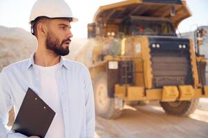 Smart person ,is with documents in hands. Man in uniform is working in the quarry at daytime photo