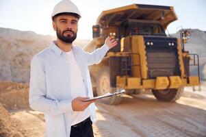 Smart, person is with ,documents in hands. Man in uniform is working in the quarry at daytime photo
