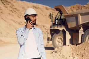Talking, by phone. Man ,in uniform is working in the quarry at daytime photo