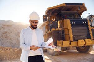 Smart man in glasses and in ,uniform is working in the quarry at daytime photo