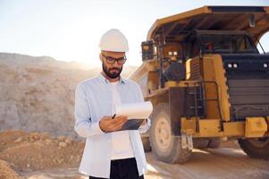 Smart, man in glasses, and in uniform is working in the quarry at daytime photo