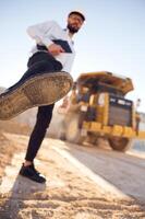 Having fun, making a kick by leg. Man in uniform is ,working in the quarry at daytime photo