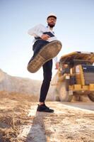 Having fun, making a kick by leg. Man, in uniform is working in the quarry at daytime photo