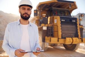 Smart person is with documents ,in hands. Man in uniform is working in the quarry at daytime photo
